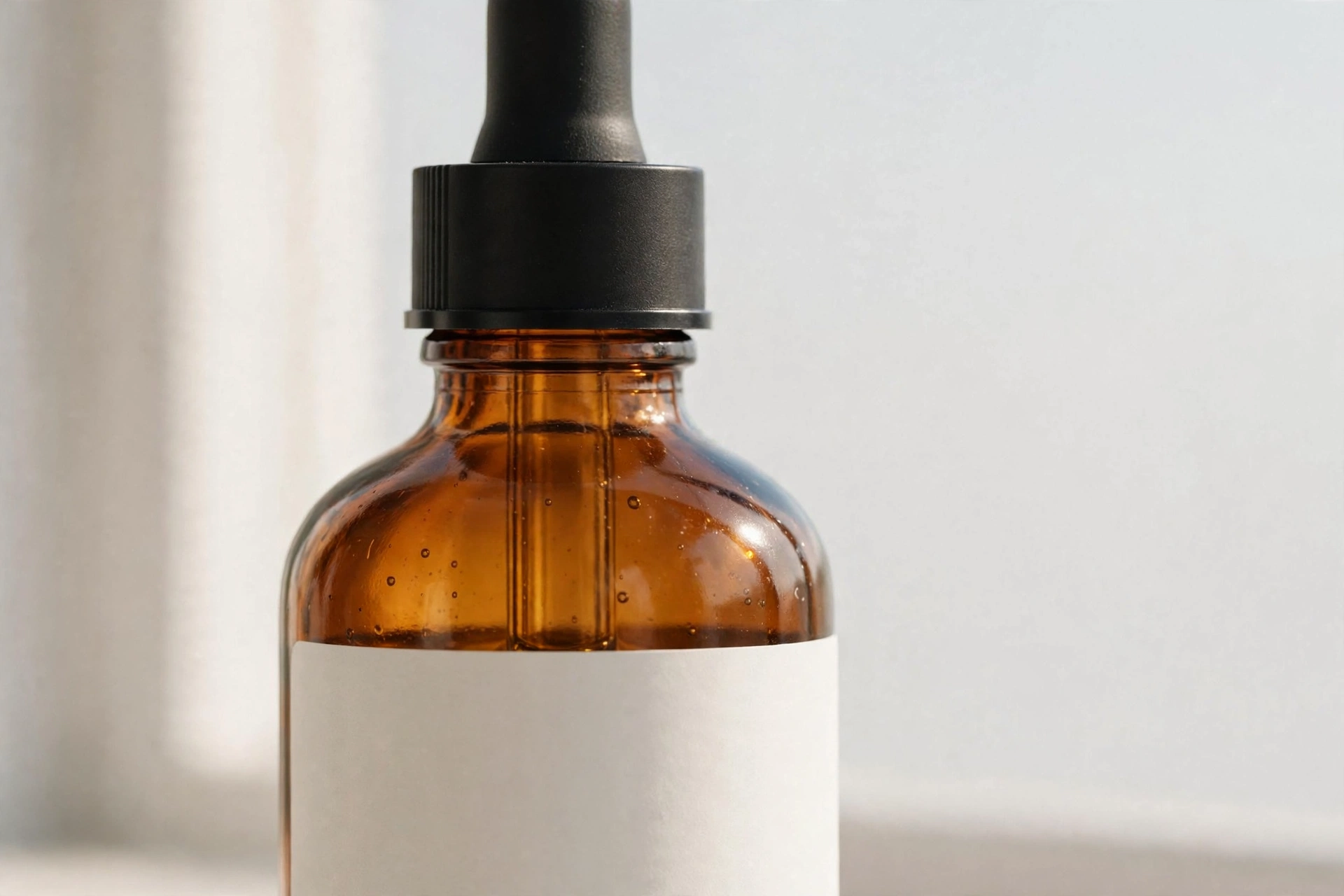 Close-up of an amber glass CBD tincture dropper bottle with a blank label