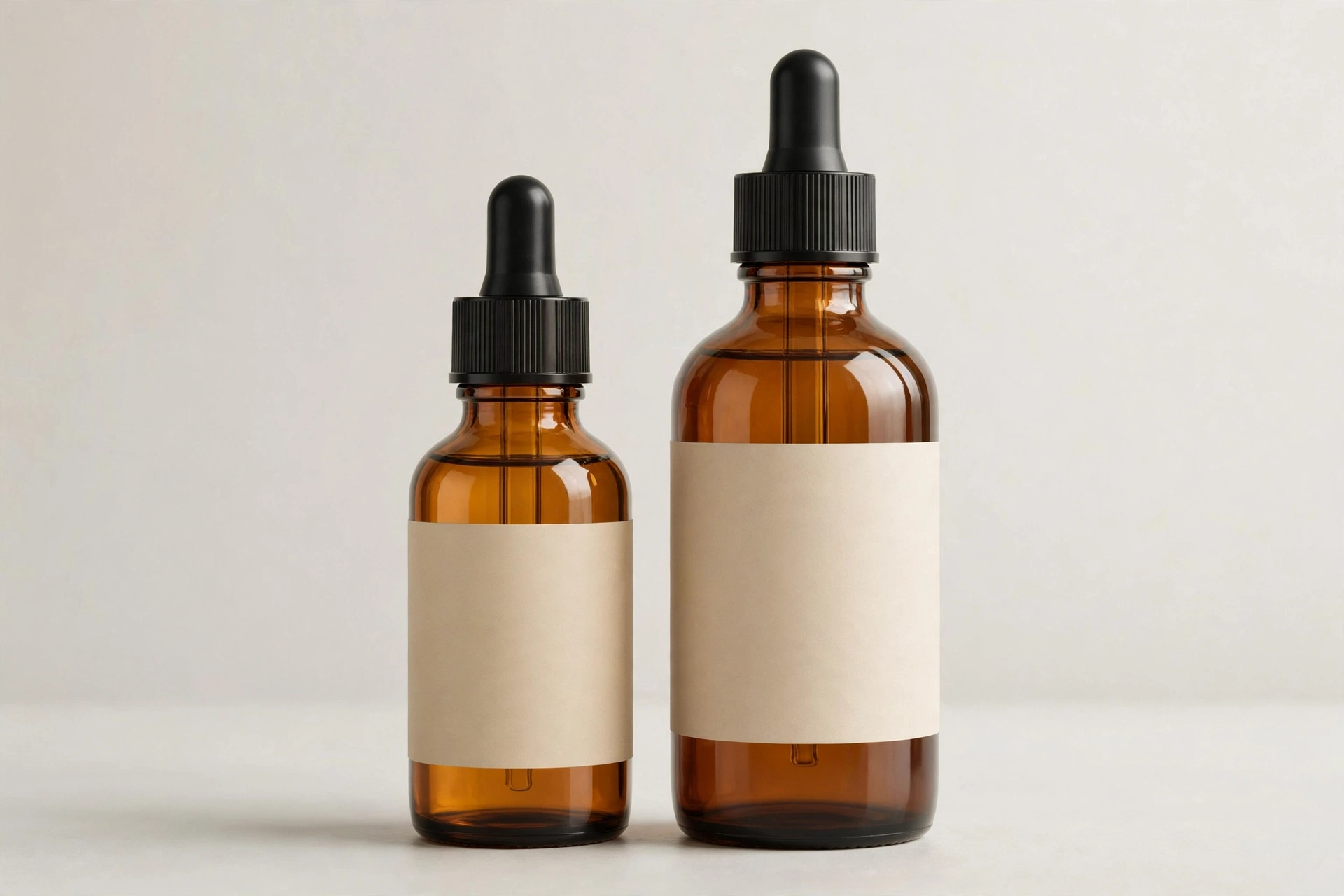Two amber CBD tincture bottles of different sizes with blank labels side by side