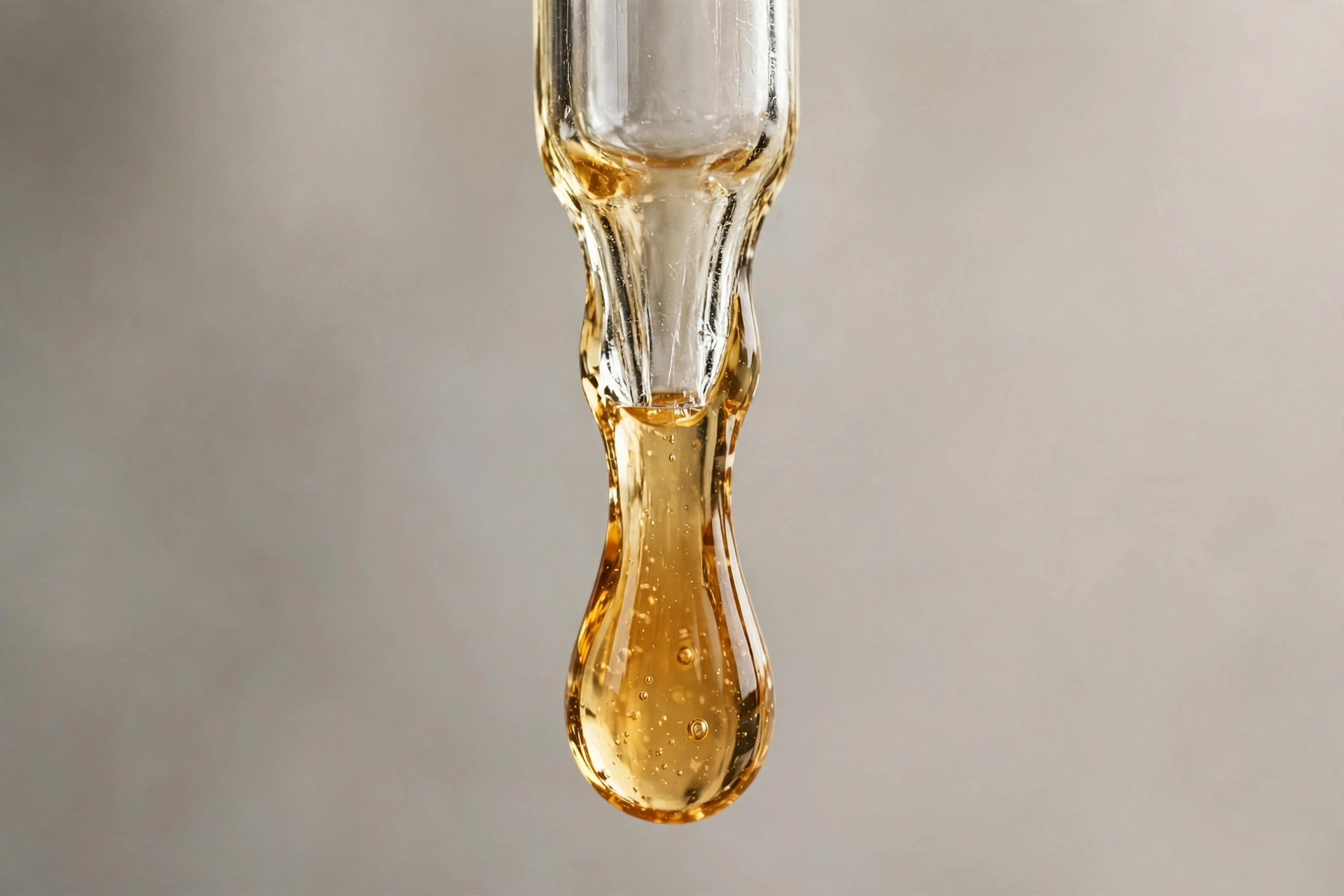 Macro close-up of thick vegetable glycerin liquid dripping slowly from a glass dropper