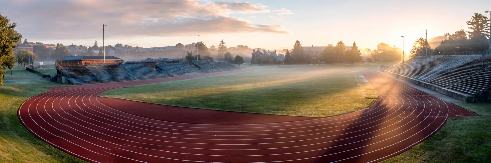 Empty university track and field stadium at sunrise, a nod to Cindy DeAngelis Grossman's track career at the University of Georgia